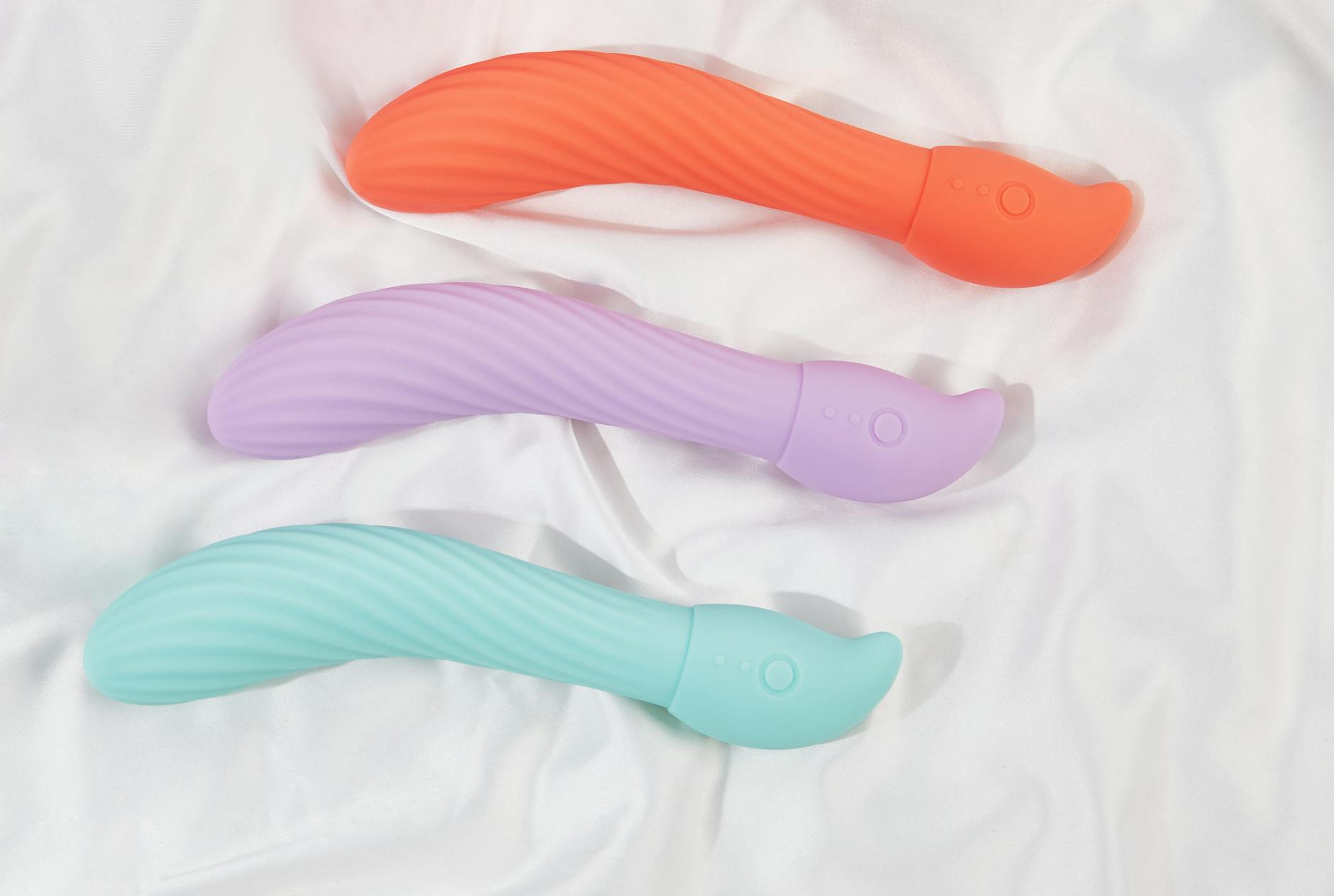 Hand hält einen orangefarbenen Vibrator vor minimalistische violette Kulisse