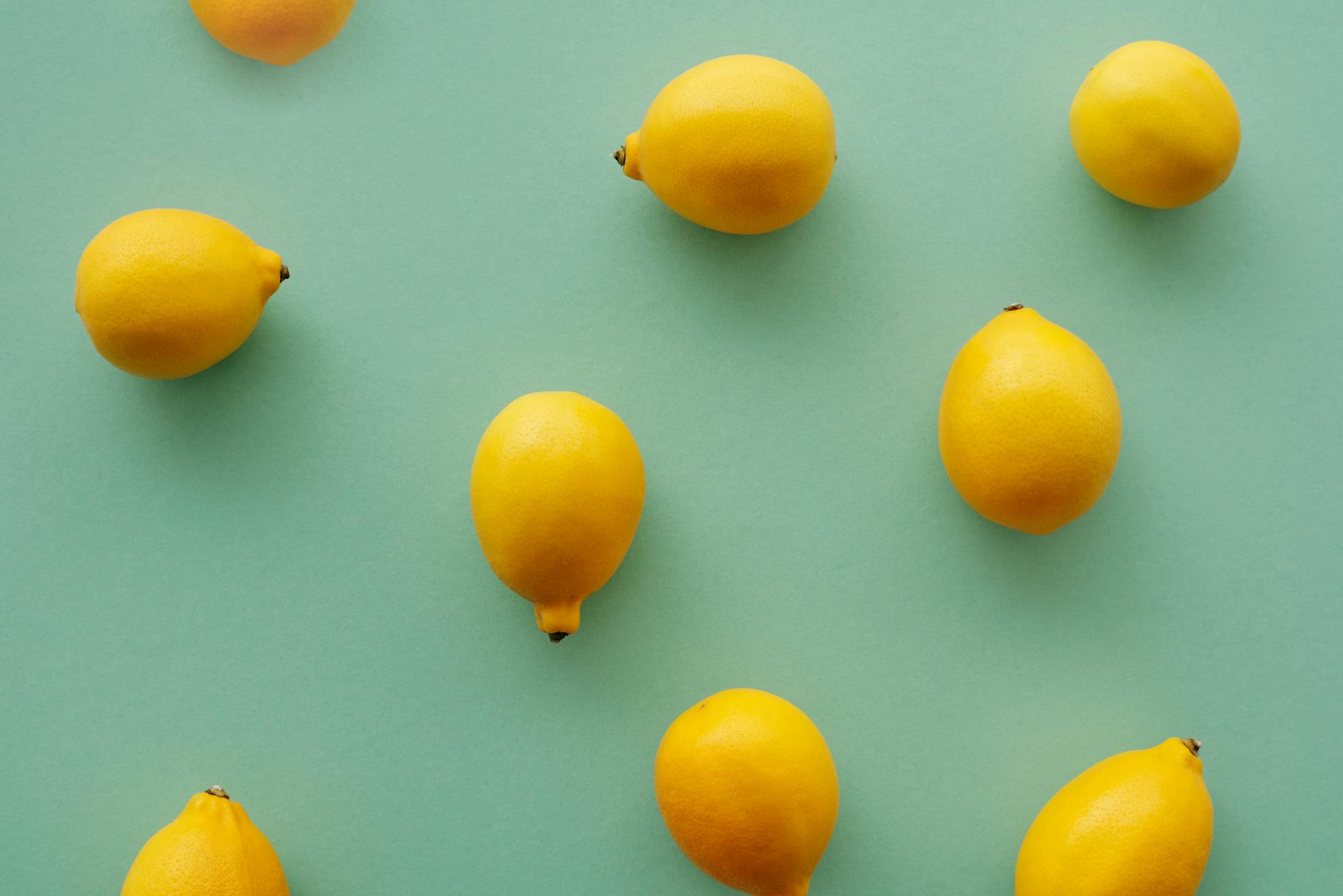 Frische gelbe Zitronen arrangiert auf pastellgrünem Hintergrund, die Frische und Vitalität symbolisieren.