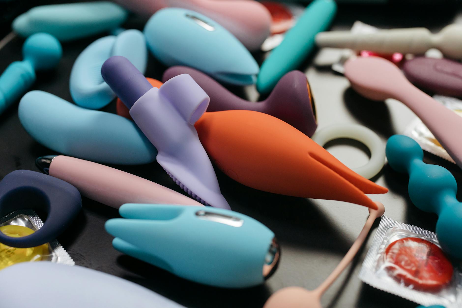Ein Nahaufnahmebild einer beeindruckenden Sammlung lebhafter Sexspielzeuge, einschließlich Vibratoren und Ringe.