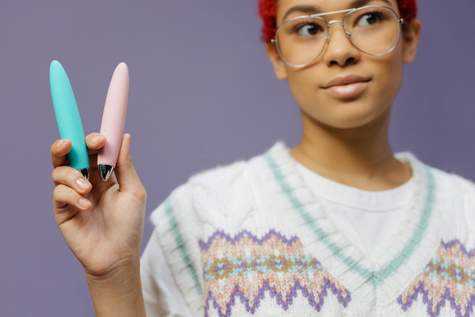 Eine Hand hält einen modernen Lemon Vibrator mit Saugtechnologie gegen einen minimalistischen lila Hintergrund