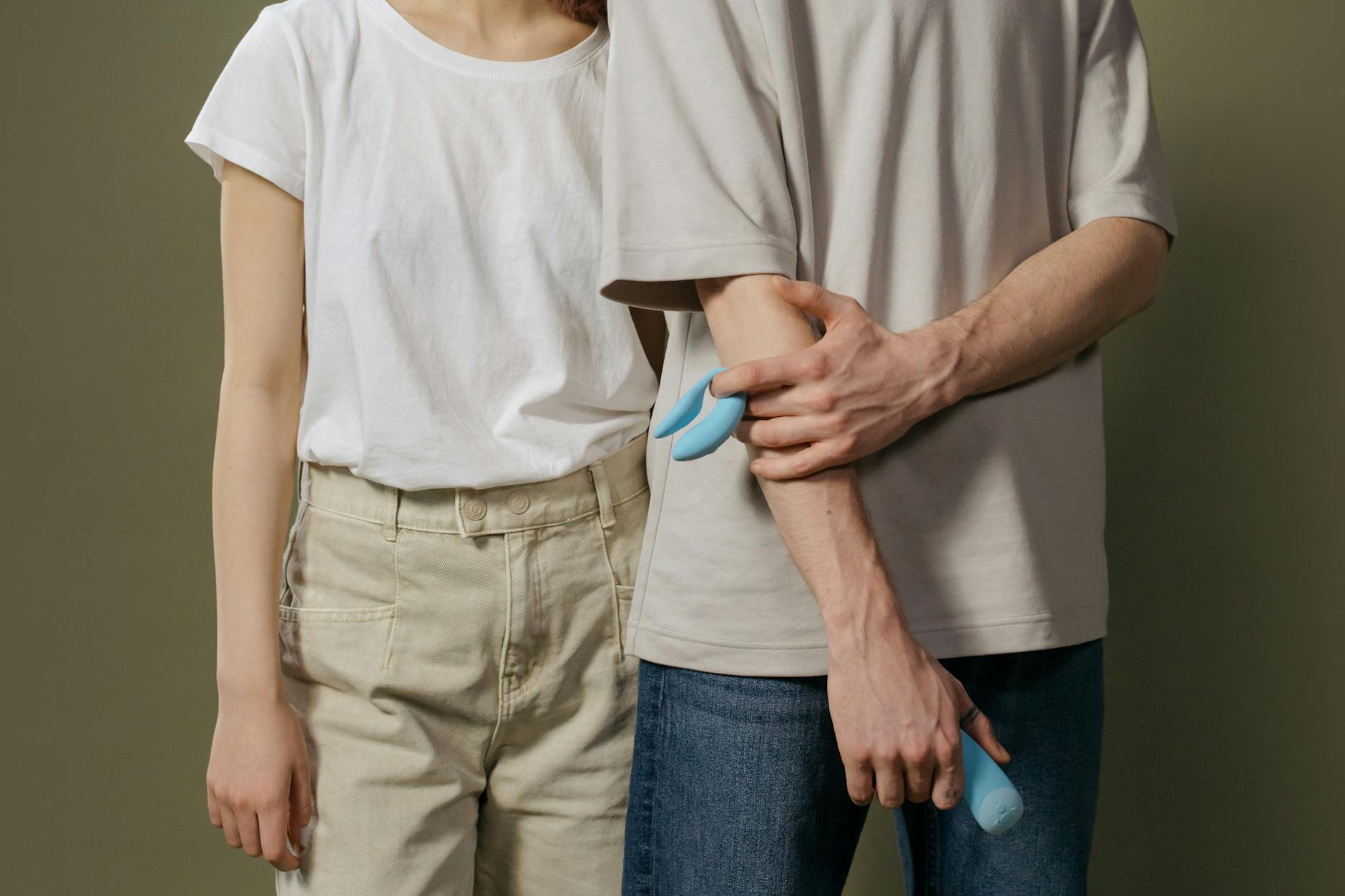 Ein junges Paar steht zusammen und hält einen modernen Vibrator, symbolisierend Vertrauen und gemeinsame Erkundung.